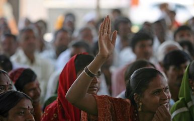 A woman raises her hand to speak at a community meeting