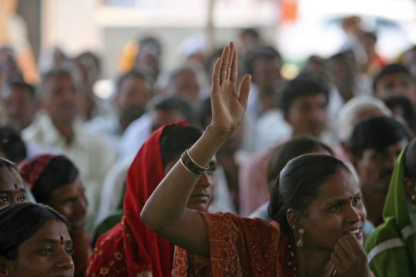 A woman raises her hand to speak at a community meeting