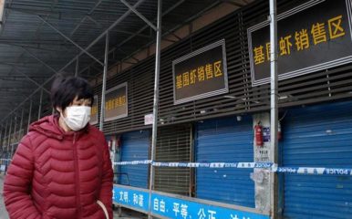 A woman in a mask walks past the closed seafood market following the coronavirus outbreak