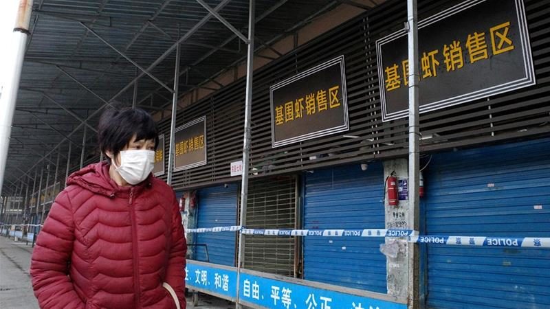 A woman in a mask walks past the closed seafood market following the coronavirus outbreak