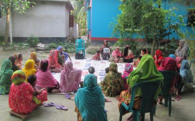 women sitting on the ground in a circle, discussing