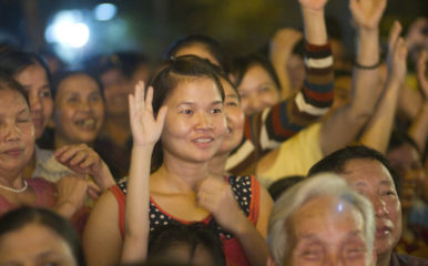 young woman in crowd holding her hand up
