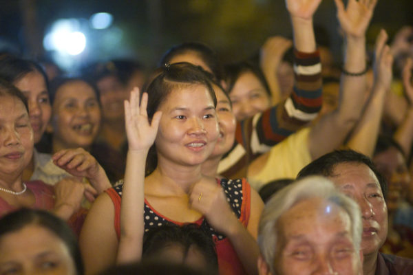 young woman in crowd holding her hand up