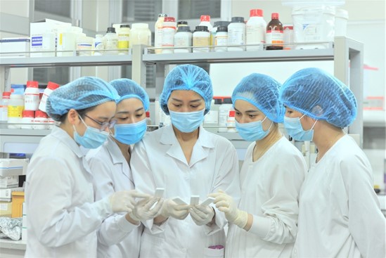 five women in lab wearing lab gea looking at test results
