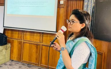 woman speaking into a mic in front of a powerpoint presentation