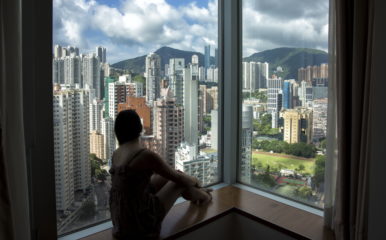 person in front of window overlooking high buildings of Hong Kong