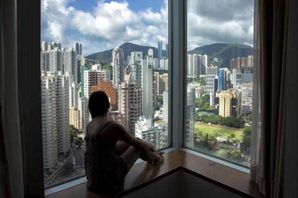person in front of window overlooking high buildings of Hong Kong