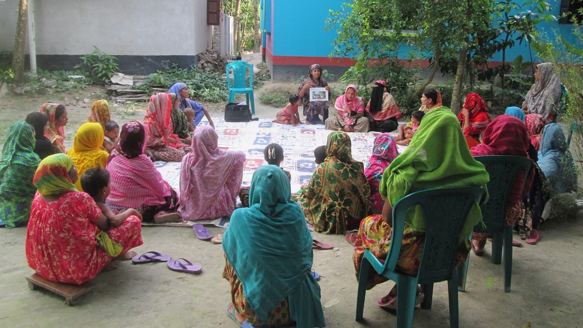 women seated in a circle on the ground taking part in an activity