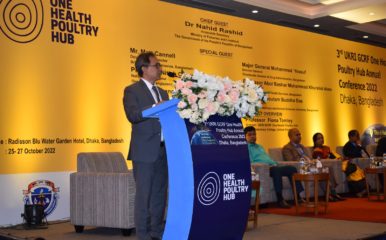 Prof Hoque at a podium beihnd a large Hub nanner detailing the conference speakers.