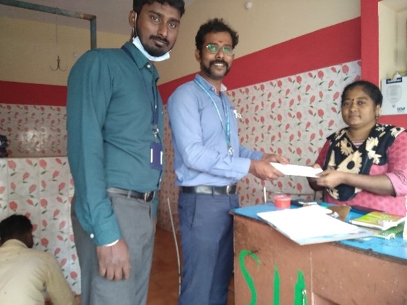 two men standing handing a document to a woman, seated