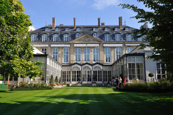 A grand mansion-style house with a lawn in the foreground