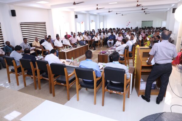 many people standing and sitting around a large rectangular table