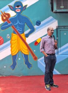 man standing in front of decorated wall, speaking